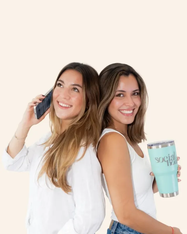 Dos integrantes del equipo de Social Hour, espalda con espalda, una al teléfono y otra con un vaso de la agencia