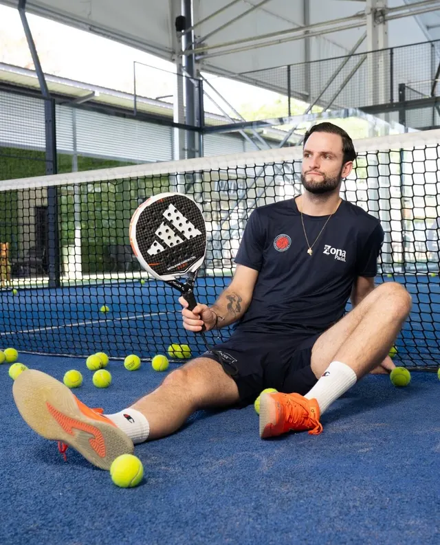 Jugador sentado en una cancha de pádel azul rodeado de pelotas