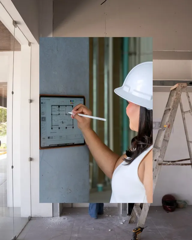 Una arquitecta con casco dibuja un plano sobre un vidrio en una obra